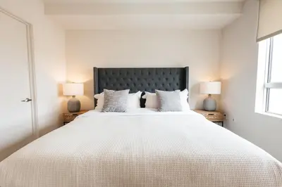 a white bedroom with a large bed with two lamps at Lovely 1 BD in West Hollywood in Los Angeles