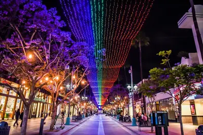 a street at night with christmas lights on trees at Splendid 2BR, 2BA Apt 12 Min Walk to SM Pier! in Los Angeles
