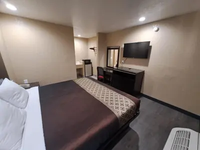 a hotel room with a bed and a desk and a television at American Inn i10 Rialto and Colton in Rialto