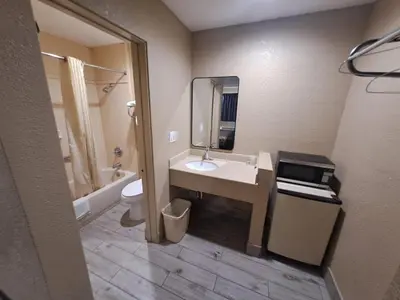 a bathroom with a sink and a toilet and a mirror at American Inn i10 Rialto and Colton in Rialto