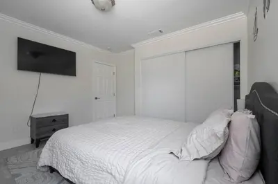 a white bedroom with a bed and a flat screen tv at Serene Home in Central Burbank in Burbank