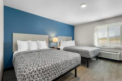 a bedroom with two beds and a blue wall at WoodSpring Suites Palmdale - Lancaster in Palmdale