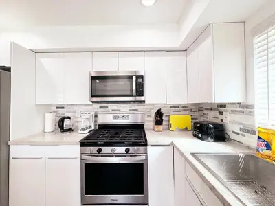 a white kitchen with a stove and a microwave at Cozy 3 BR Townhouse with Balcony in Los Angeles