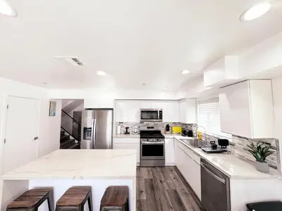 a white kitchen with wooden floors and white cabinets at Cozy 3 BR Townhouse with Balcony in Los Angeles