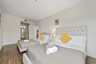two beds in a room with white and yellow pillows at Le Reve , 5 min to the beach Luxury Condo in Los Angeles
