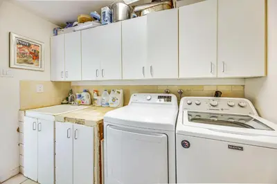 a kitchen with white cabinets and a washer and dryer at Vibrant Home with Patio - Near Santa Monica Pier! in Los Angeles
