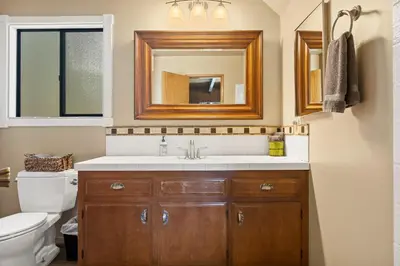 a bathroom with a sink and a toilet and a mirror at Pine Oaks Cabin in Lake Arrowhead