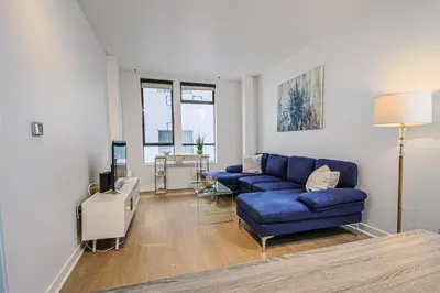 a living room with a blue couch and a tv at The Carlton - Modern-Lux 2 Master Suites-Secure Bldg & Parking- 5 BLKS to Ocean Ave in Los Angeles