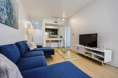 a living room with a blue couch and a tv at The Carlton - Modern-Lux 2 Master Suites-Secure Bldg & Parking- 5 BLKS to Ocean Ave in Los Angeles