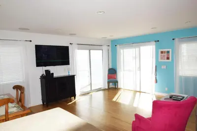 a living room with a flat screen tv and pink chairs at Malibu Private Beach Apartments in Malibu