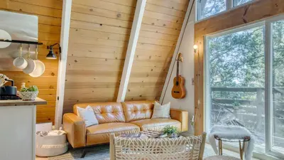 a living room with a leather couch and a guitar at A-Frame Retreat Chic and Modern Forest Views Hammock Outdoor Dining Decks in Lake Arrowhead