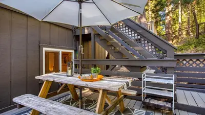 a wooden table with an umbrella on a deck at A-Frame Retreat Chic and Modern Forest Views Hammock Outdoor Dining Decks in Lake Arrowhead
