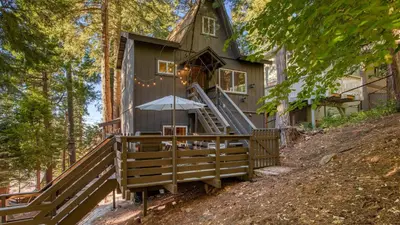 a tree house in the woods with an umbrella at A-Frame Retreat Chic and Modern Forest Views Hammock Outdoor Dining Decks in Lake Arrowhead