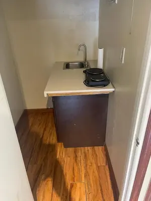 a small kitchen with a sink and a wooden floor at UCLA Thurston in Los Angeles