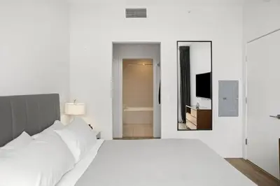 a white bedroom with a large bed and a mirror at 2 Bed 2 Bath Contemporary High Rise DTLA Living in Los Angeles