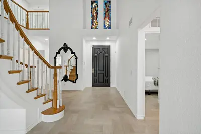 a hallway with a black door and a stair case at Luxury Waterfront Home in the Heart of the Harbor in Huntington Beach