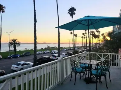 a balcony with a table and chairs and a parking lot at Ocean Boulevard Beachfront Home in Long Beach