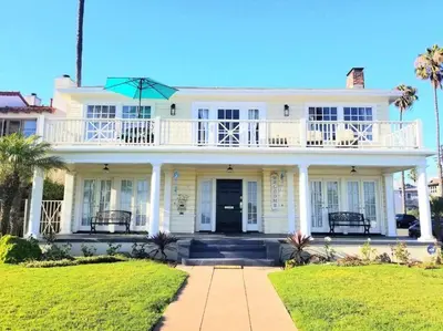 a white house with a balcony on top of it at Ocean Boulevard Beachfront Home in Long Beach