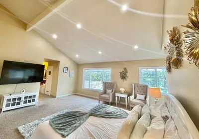 a bedroom with a large bed and a flat screen tv at Stunning Panoramic Waterfront Pool Home Escape in Anaheim