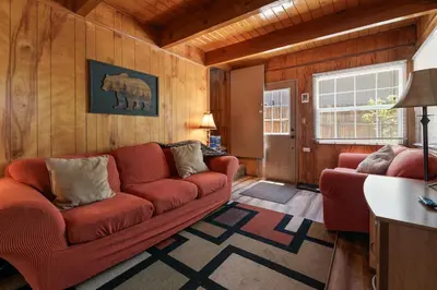 a living room with a red couch and wooden walls at Chateau Rouge - Walk to Lake & Village, AC, Pet Friendly! in Big Bear Lake