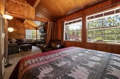 a bedroom with a bed and a couch and windows at Chateau Rouge - Walk to Lake & Village, AC, Pet Friendly! in Big Bear Lake