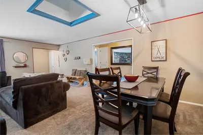 a dining room and living room with a table and a couch at Wanderlust - Hot Tub, Foosball, Ping Pong, Walk to Lake & Village! in Big Bear Lake