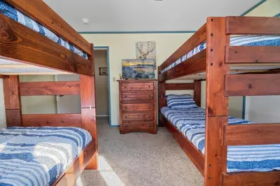 a bedroom with two bunk beds and a dresser at Wanderlust - Hot Tub, Foosball, Ping Pong, Walk to Lake & Village! in Big Bear Lake