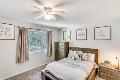 a bedroom with a bed and a ceiling fan at 1 Mi to Lake Crestline Cabin with Deck and Gas Grill! in Crestline
