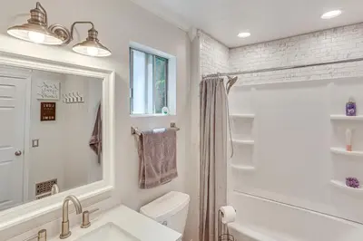 a white bathroom with a sink and a shower at 1 Mi to Lake Crestline Cabin with Deck and Gas Grill! in Crestline