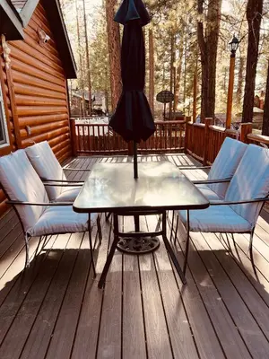 a table on a deck with chairs and an umbrella at Château Bouli - 4 Season Escape and Games Room in Big Bear Lake