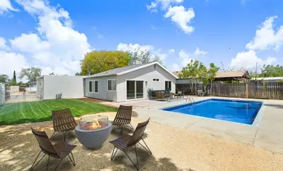 a backyard with a pool and chairs and a house at Lancaster Pool Home in Lancaster