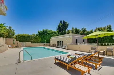 a swimming pool with lounge chairs and an umbrella at 2 Mi to Hollywood Condo with Pool and Hot Tub Access in Los Angeles