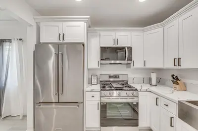 a kitchen with white cabinets and a stainless steel refrigerator at 2 Mi to Citadel Outlets! East LA Retreat Near I-5 in Los Angeles