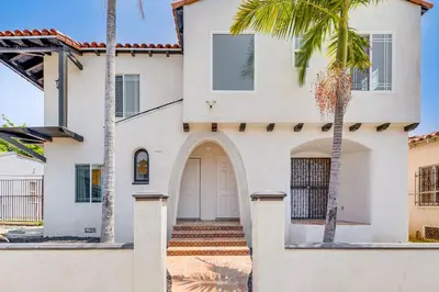 a white house with palm trees in front of it at 2 Mi to Citadel Outlets! East LA Retreat Near I-5 in Los Angeles