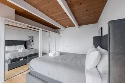 a white bedroom with two beds and a wooden ceiling at Hollywood Hills Retreat with Panoramic View in Los Angeles