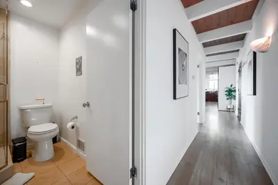 a white bathroom with a toilet and a hallway at Hollywood Hills Retreat with Panoramic View in Los Angeles