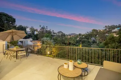 a balcony with a table and chairs and an umbrella at Belden Modern Villa in Los Angeles