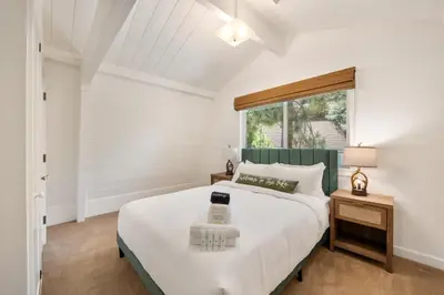 a white bedroom with a large bed and a window at Scout's Lakehouse Retreat by Colby & Conrad in Lake Arrowhead