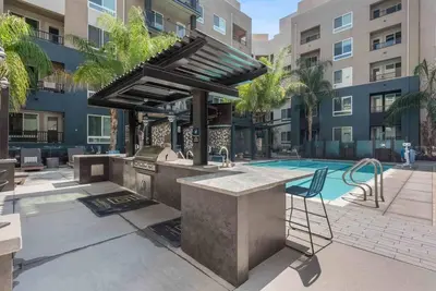 an outdoor kitchen with a grill and a swimming pool at Modern and Lavish apartment in Glendale