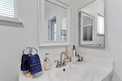 a white bathroom with a sink and a mirror at Oasis Condo on the Fairway in Victorville