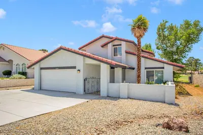 a house with a palm tree and a driveway at Oasis Condo on the Fairway in Victorville
