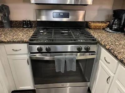 a stainless steel stove in a kitchen with white cabinets at Travel Haven at Miracle Mile- 110 in Los Angeles