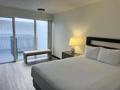 a hotel room with a bed and a balcony at MC Pacific Inn & Suites Torrance in Torrance