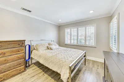 a bedroom with a bed and a dresser and windows at Game Room, Pool! Family Home 25 Mi to Disneyland in West Covina