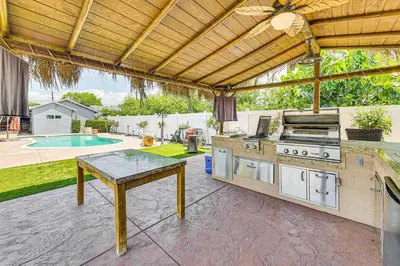 an outdoor kitchen with a grill and a table at Game Room, Pool! Family Home 25 Mi to Disneyland in West Covina