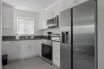 a kitchen with white cabinets and a stainless steel refrigerator at Prime new beautiful studio in burbank in Burbank