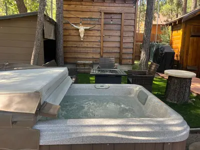 a hot tub in a yard next to a cabin at The Nest On Towne Trail - Hot Tub, BBQ, Fire Pit in Big Bear Lake