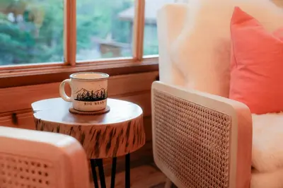 a coffee cup sitting on a table next to a chair at The Nest On Towne Trail - Hot Tub, BBQ, Fire Pit in Big Bear Lake