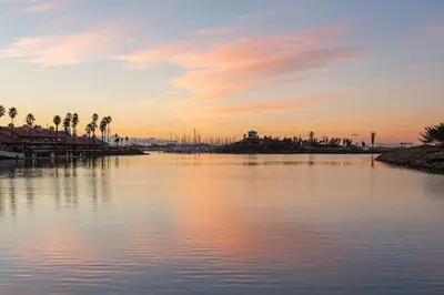 a large body of water with palm trees and a sunset at Beautiful Resort in Harbortown Point 1BD near Marina Park in Ventura