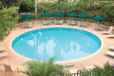a large swimming pool with chairs and green umbrellas at Beautiful Resort in Harbortown Point 1BD near Marina Park in Ventura